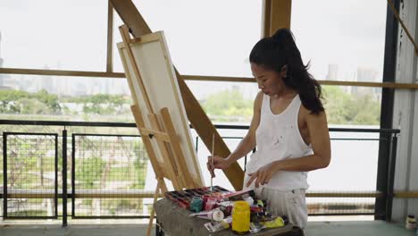 woman painting on a rooftop with an urban background