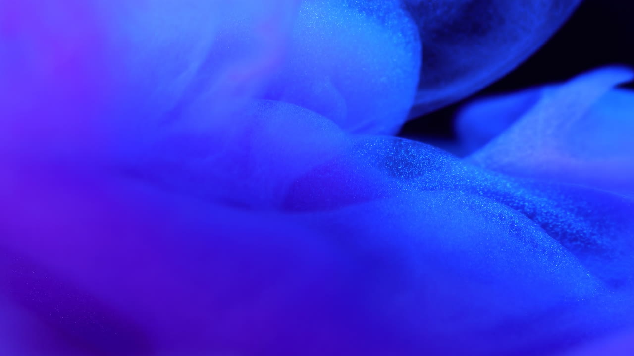 Živý modrý inkoustový oblak vířící v hlubokém černém studiu, zpomalené makro pigmentu ve vodě se sametovostí.