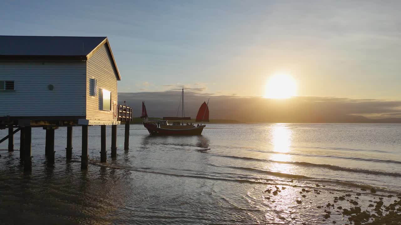 A serene sunset scene with a beach house and pier, captured in golden hour lighting, showcasing tranquil coastal beauty