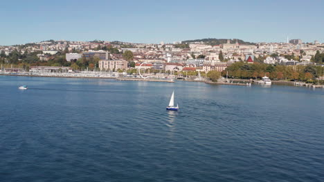 Drone-flying-over-sailboat-near-harbor-in-Lausanne,-Switzerland