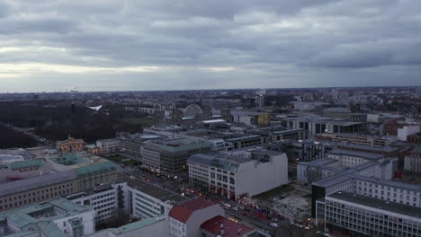 Aerial-footage-of-large-city-at-dusk.-Unter-den-Linden-street-and-Brandenburg-gate-from-height.-Berlin,-Germany