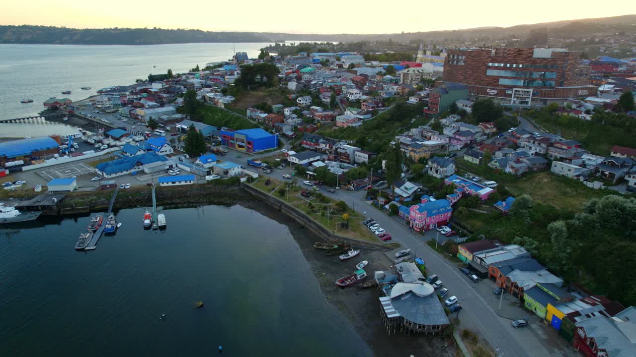 orbita aérea que establece la costa de castro chiloe con el sol poniéndose en el fondo, chile