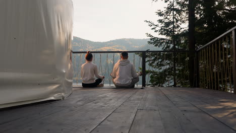 couple meditating on a deck overlooking a lake