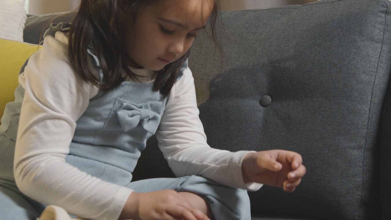 niña en espectro asd en casa sentada en un sofá resolviendo rompecabezas de forma 1