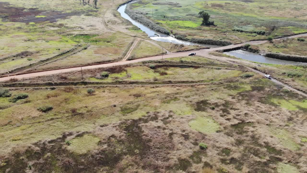 toma aérea de un dron del río que fluye bajo un puente remoto de grava en johannesburgo, sudáfrica