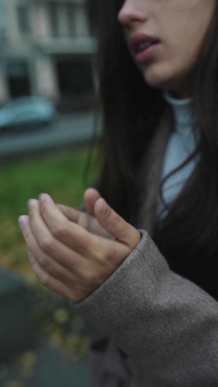 가을 에 야외 에서 손 을 따뜻 하게 하는 여자