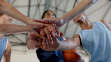basketball team huddling, stacking hands together before game, showing unity