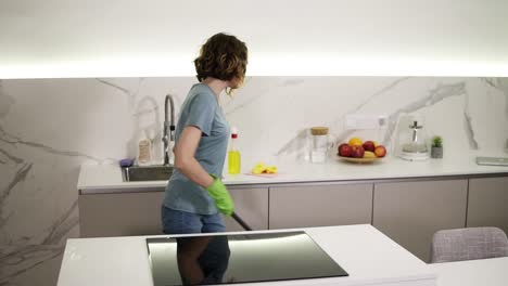 happy young woman cute housewife is washing floor using protective gloves at home in kitchen enjoying housework. people, modern lifestyle and youth concept