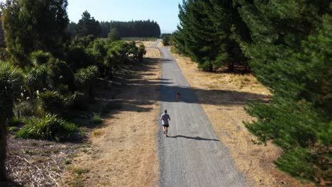 following man going for a run with his dog on a dirt track in the woods.