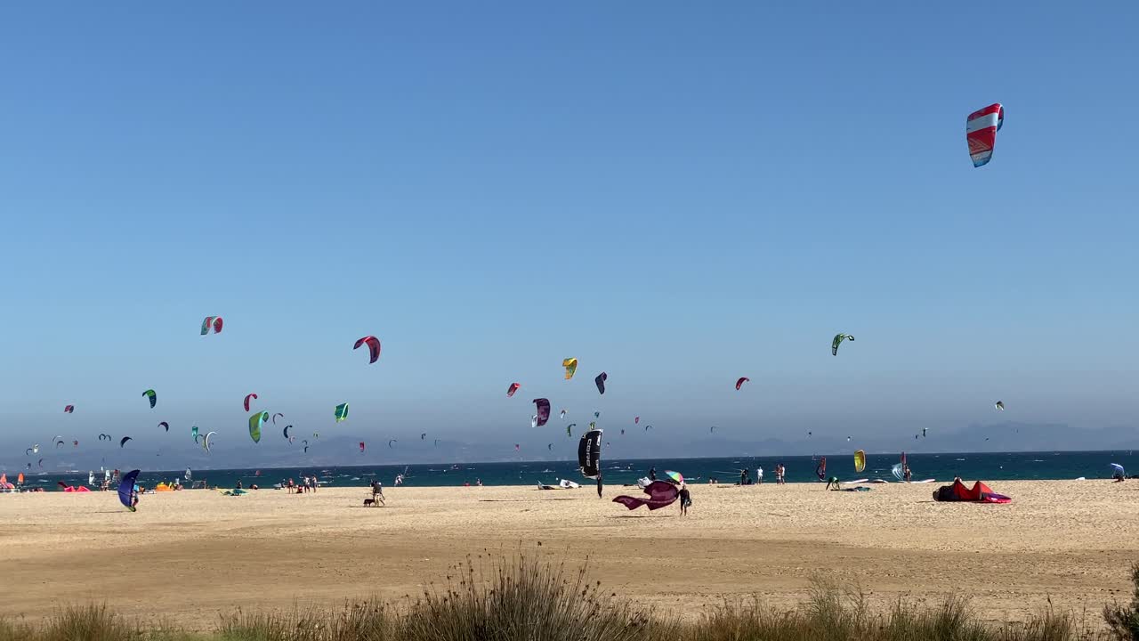 Slow motion shot of the beach of Tarifa with people practicing Kite Surf.