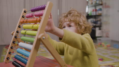 little boy playing with a panel moving wooden pieces in classroom in a montessori school 1