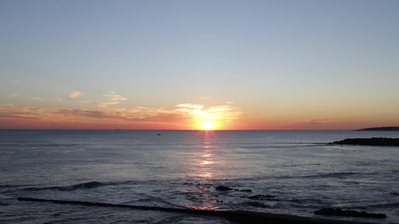 서퍼와 보트가 있는 바다 위의 놀라운 일몰