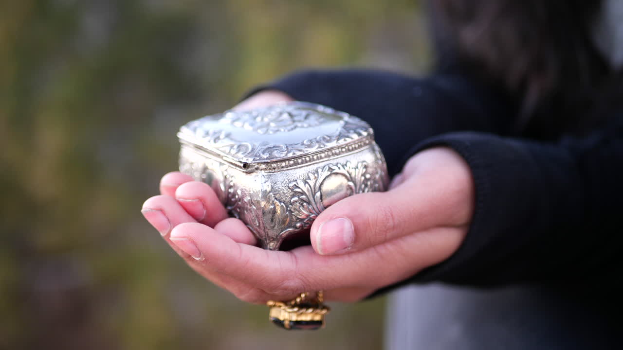primer plano de una mujer sosteniendo en sus manos una linda caja de joyería vintage plateada