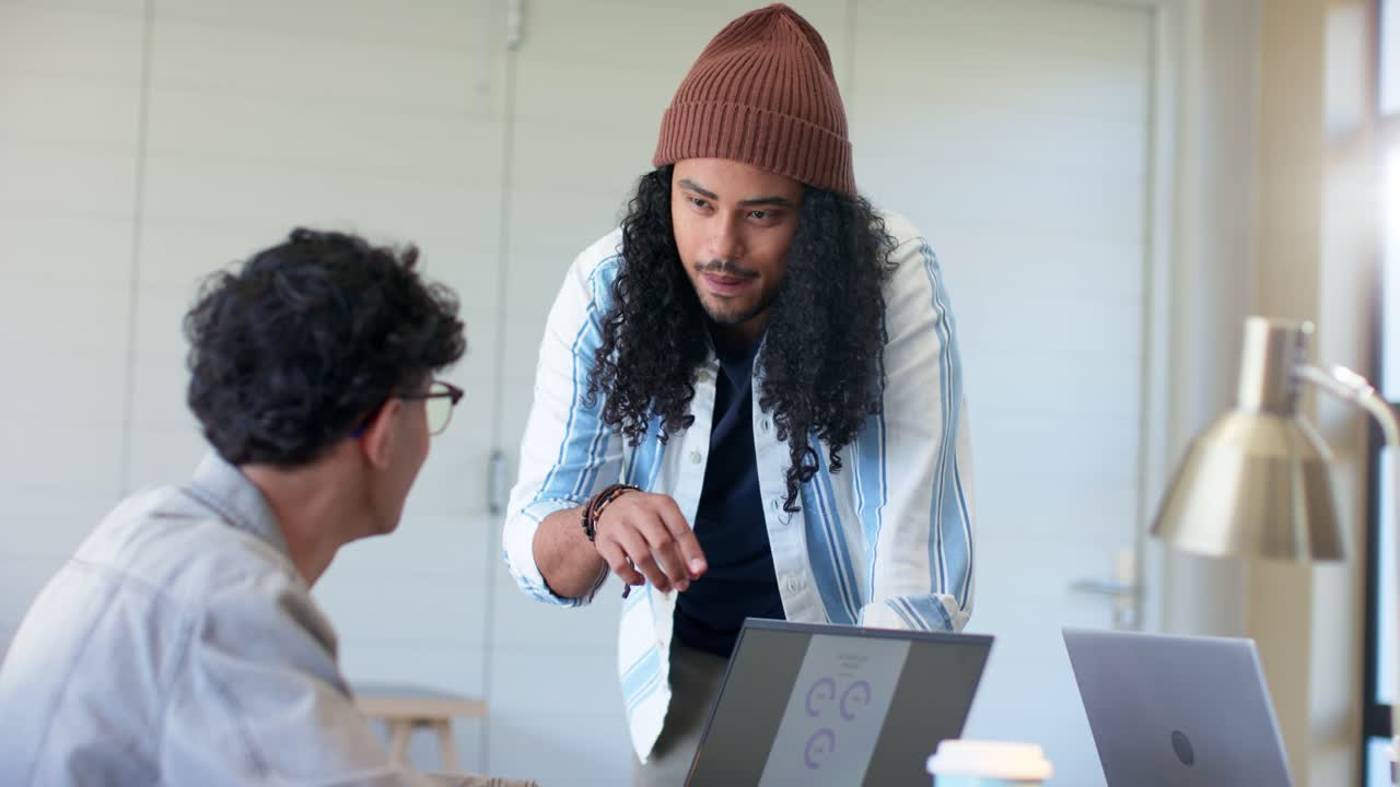 Diverse coworkers reviewing charts at table colleague approaching pointing at laptop gauge metrics
