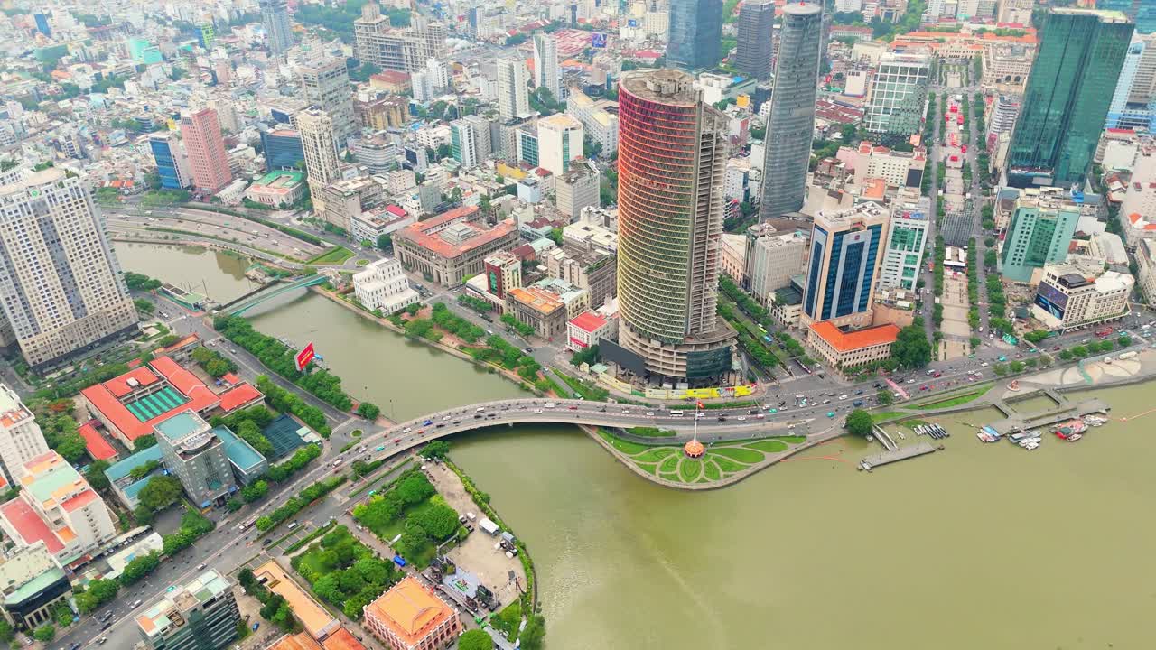 Aerial view of bustling urban landscape with a tree-lined boulevard running between towering skyscrapers, alongside a winding river, showcasing the vibrant city life and architecture