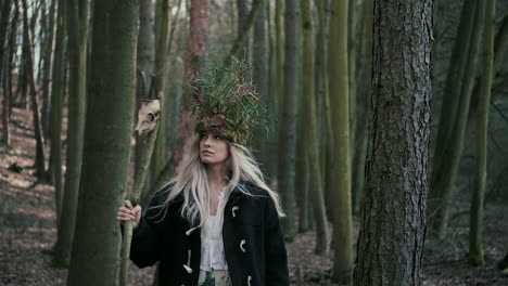 Queen-of-forest-with-skull-on-stick-walking-between-trees,-front-dolly-shot