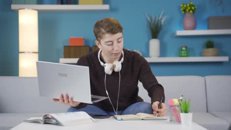 student studying on laptop taking notes.