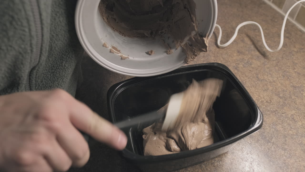 sacando helado de chocolate casero fresco en un recipiente, de cerca, de mano