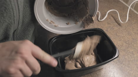 scooping fresh homemade chocolate ice cream into container, close up, handheld