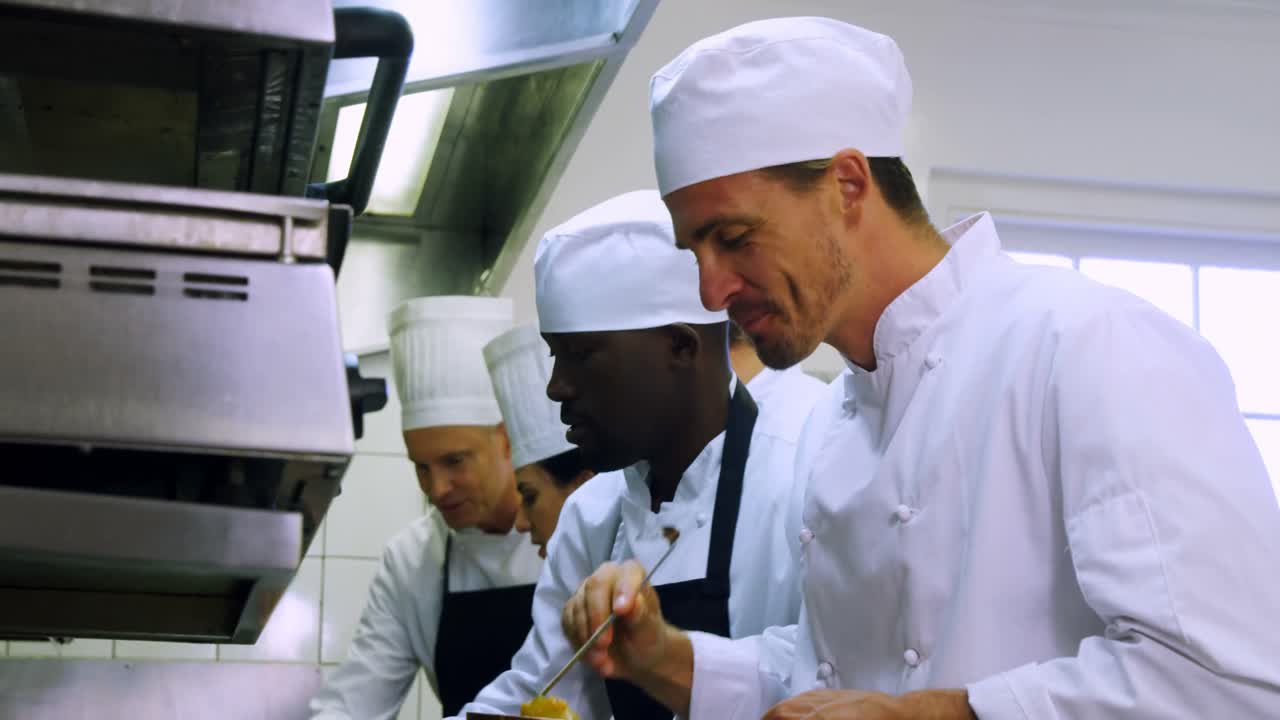 equipo de chefs preparando comida en la cocina comercial 4k