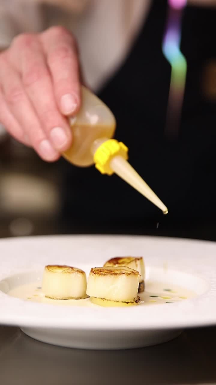 Scallops being plated with sauce