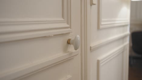 close up shot of female hands rotating door knob before opening a white door in a house