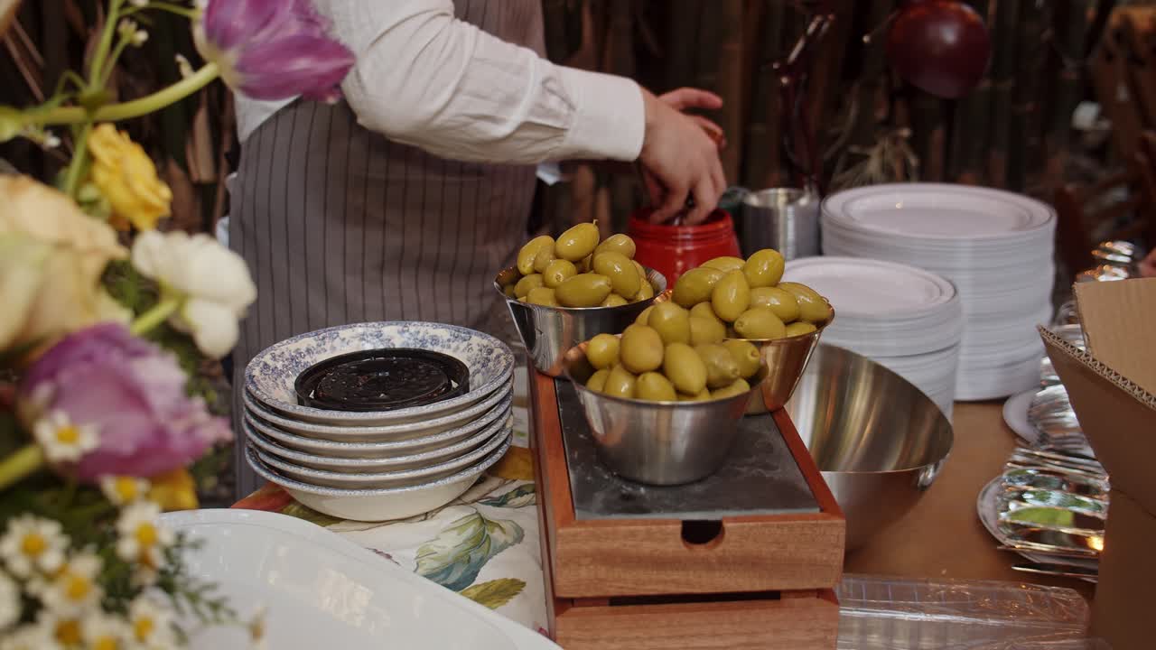 el chef pone aceitunas verdes en una taza de metal de bronce con la mano
