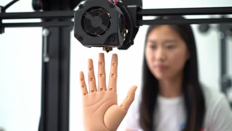 a close-up look at an advanced robotic hand, being demonstrated by a focused individual in a modern 3d printing environment, showcasing innovative technology and skill