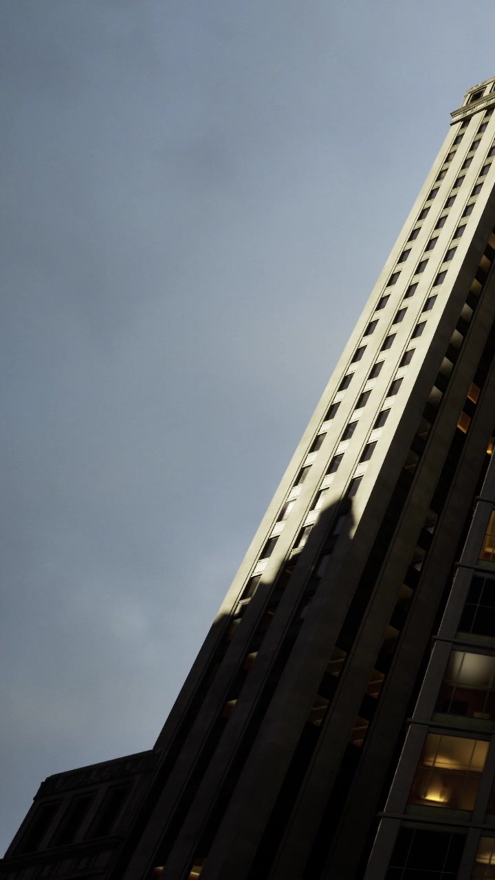 Edificio alto proyecta sombra en la acera bajo un cielo gris en una zona urbana.