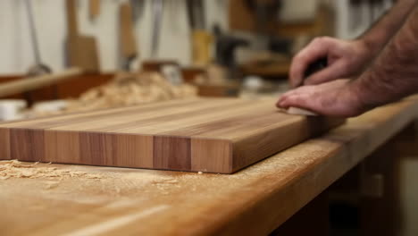 hands working on a wooden cutting board in a workshop