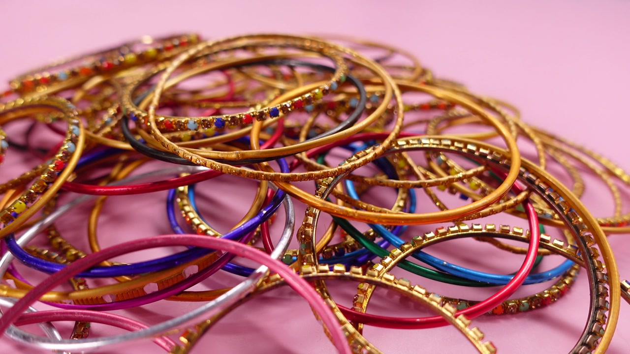 Vibrant Gold and Colorful Bangles on a Pink Surface