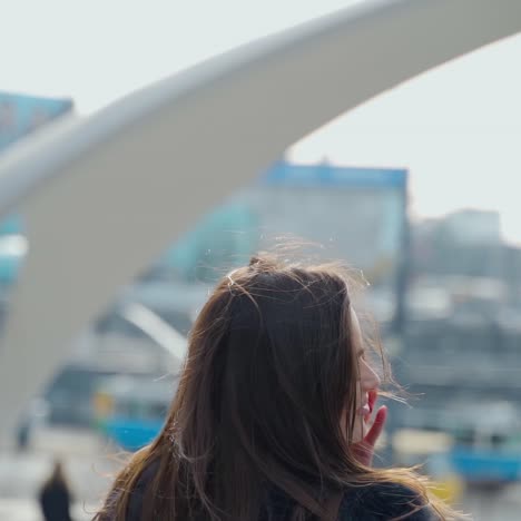 portrait of a beautiful woman with long hair. dark-haired lady talking on the phone and posing to camera on a city background. slow motion.