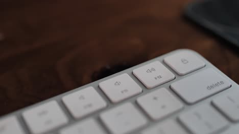 Man-hand-pressing-volume-up-button-on-a-white-keyboard