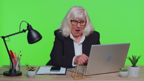 worried senior businesswoman sits at workplace avoid working playing racing or shooter video games