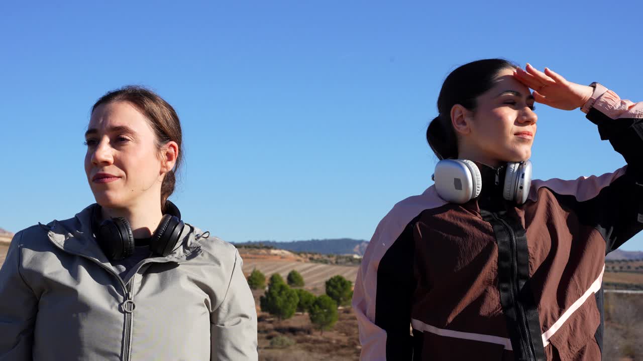 Two female runners taking off their headphones and highing-five like a team
