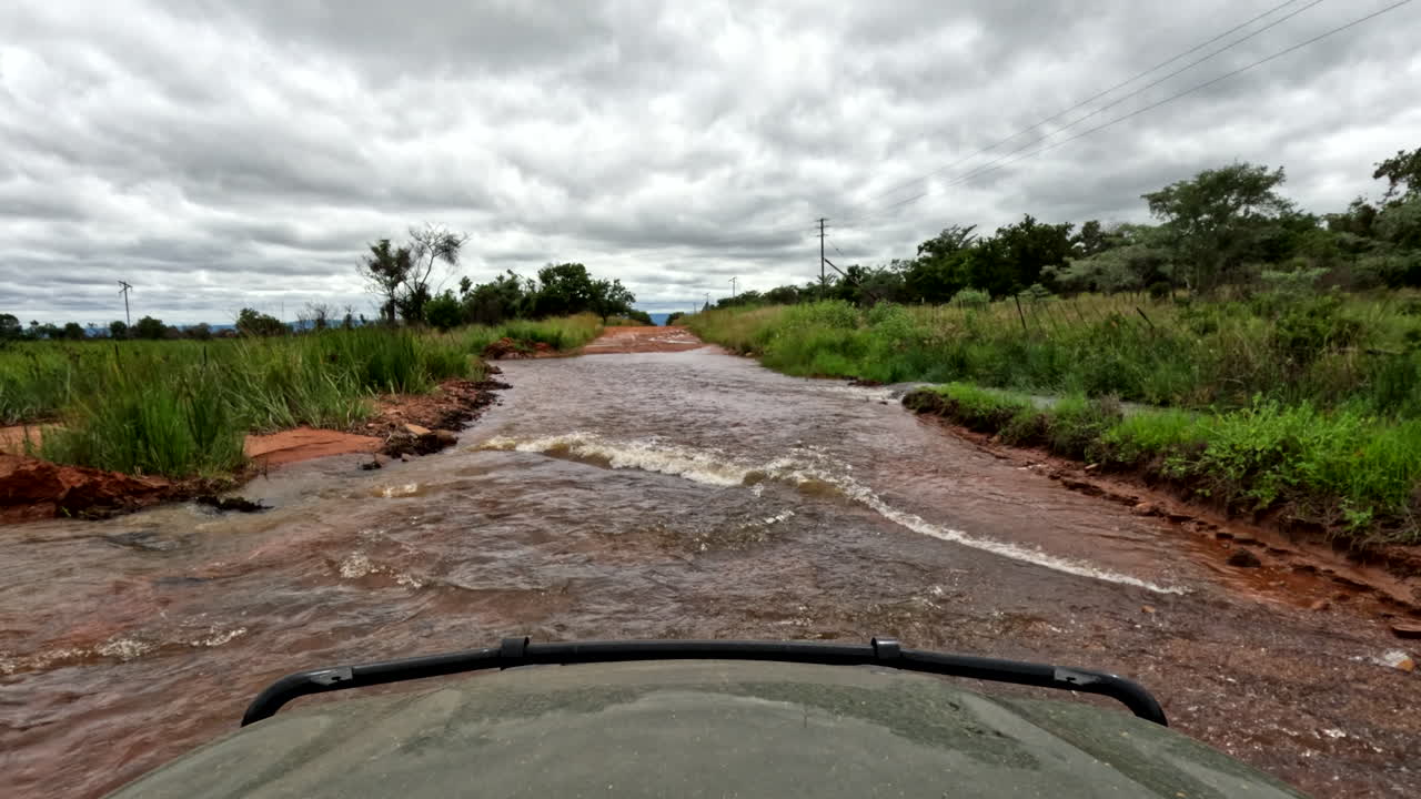 POV - 4x4 safari truck drive through flooded dirt road crossing with strong flow