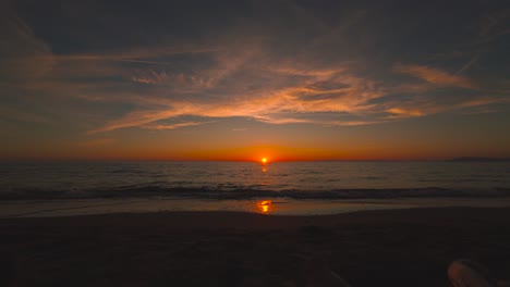 Puesta-De-Sol-En-La-Playa-De-Arena-Con-Coloridas-Nubes-Del-Cielo,-Sol-Rojo-De-La-Tarde,-Amplio-Mar-Panorámico-En-Toscana,-Italia