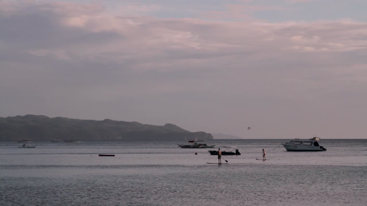 보트와 사람들이 카약을 노를 젓는 필리핀 보라카이 해변의 넓은 사진