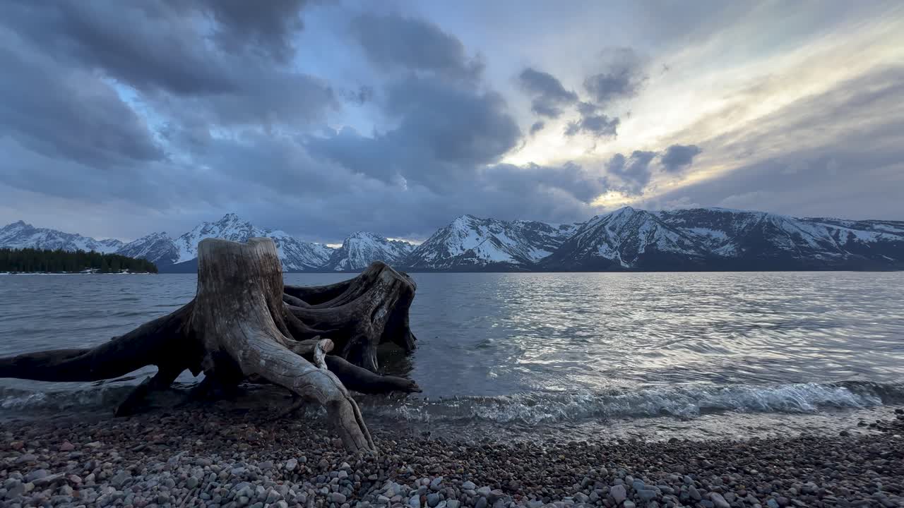 Scenic sunset at Grand Teton National park from waters edge . Cinematic clouds over the snowy winter mountain peaks