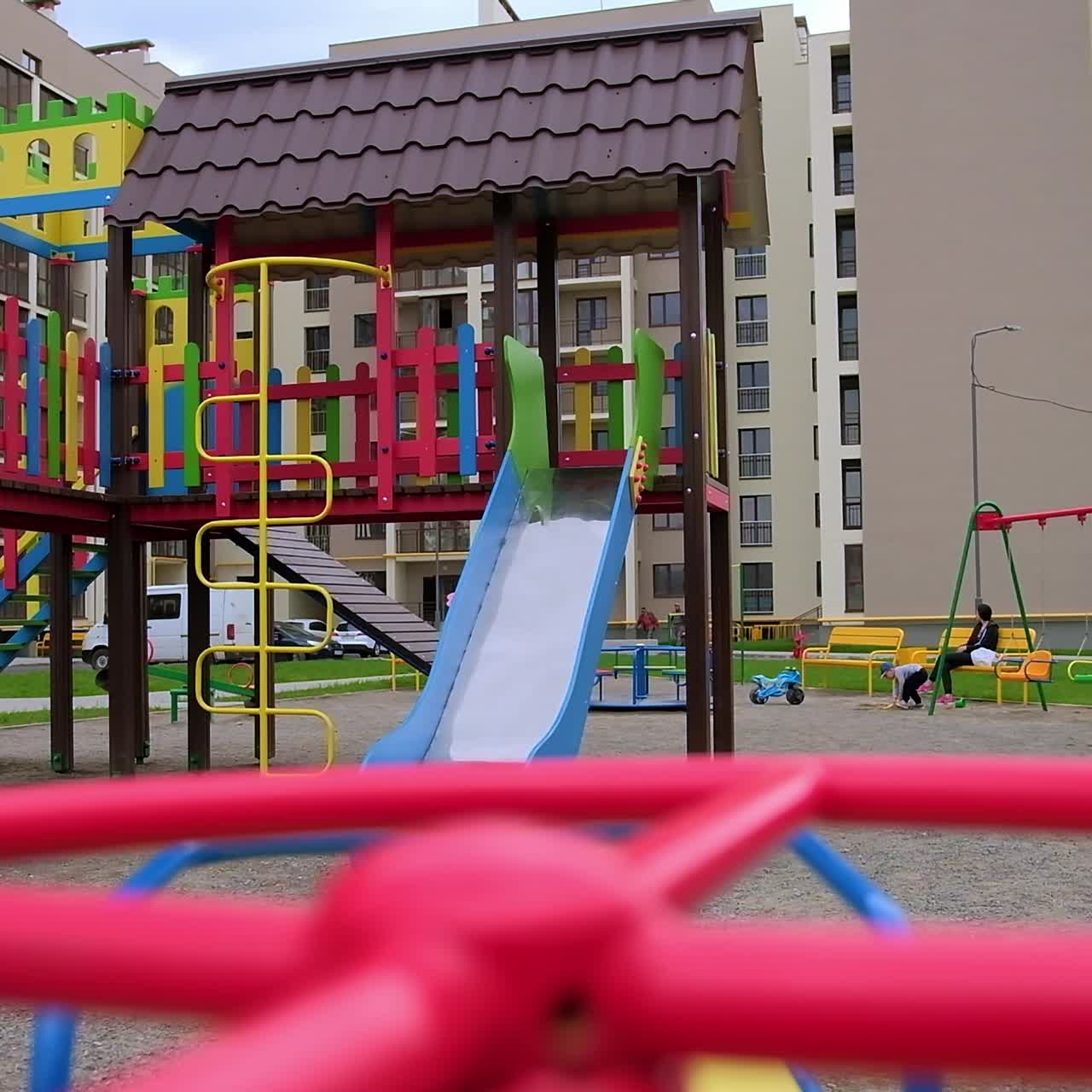 Swinging on the children's playground. Bright kid's territory in the middle of residential area of blocks of flats