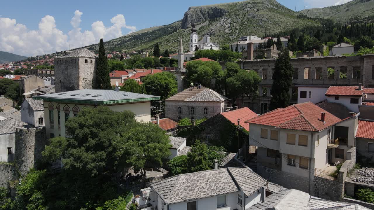 오스만 제국의 역사적인 건물들 사이에 있는 모스타르 다리의 드론 뷰, 역사적인 다리를 방문하는 관광객들