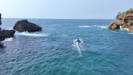 drone shot following the fisherman boat running to the ocean. the sea water is blue with a horizon that blends with the blue sky. aerial view of nautical tropical beach. ngrenehan beach, indonesia.