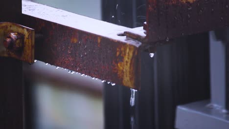 close-up view of rusty iron beam dripping water during rainfall. calm rainy weather, perfect for mood, nature or urban decay themes
