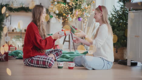 Exhilarated-sisters-exchanging-Christmas-presents-on-floor-at-home