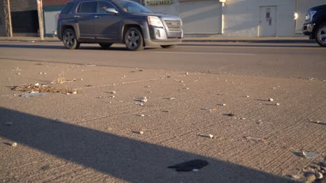 cámara lenta de cerca de vidrio roto en la acera en el lado este de detroit con coches que pasan en el fondo