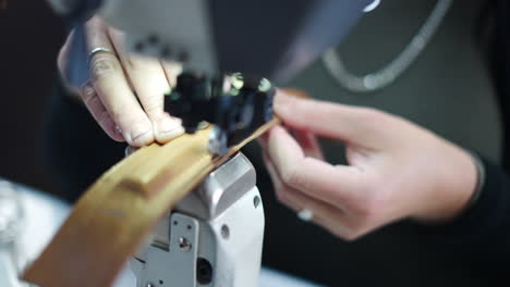 close-up of hands operating a sewing machine working with leather
