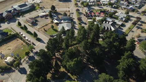 aerial rising over a pine tree octagonal square in the middle of trevelin town, patagonia argentina