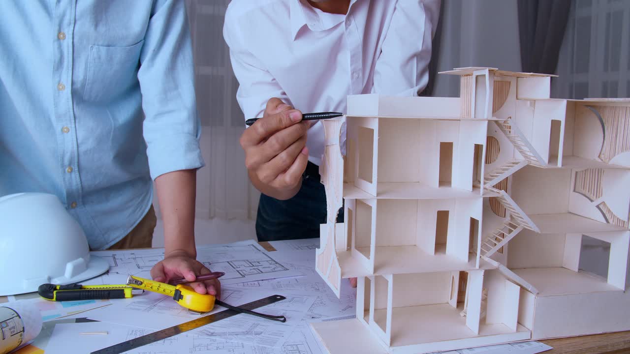 Two Male Architects In Office Discussing Construction Project