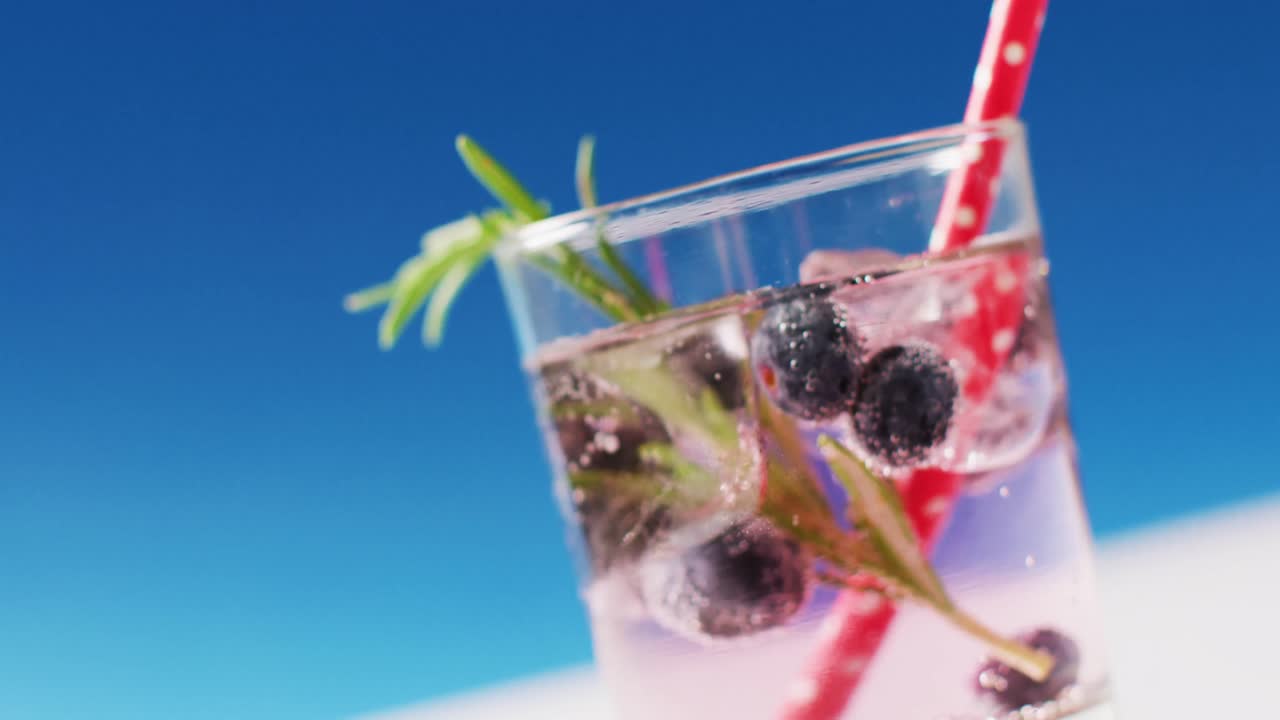 파란색 배경 에 블루베리 가 있는 투명 한 음료 의 클로즈업