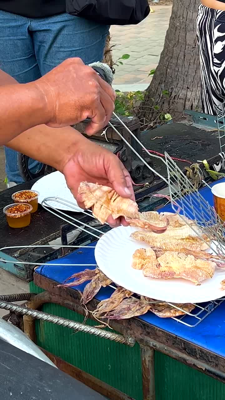 продавец грилирует и подает еду на улице.